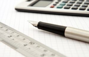 A pen, calculator, and ruler on graph paper.