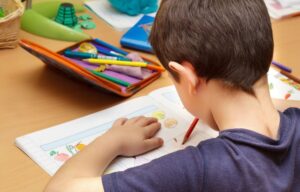 A child looking at a workbook and writing in it during a class