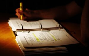 Three-ring binder open in the dark with somebody highlighting unreadable text